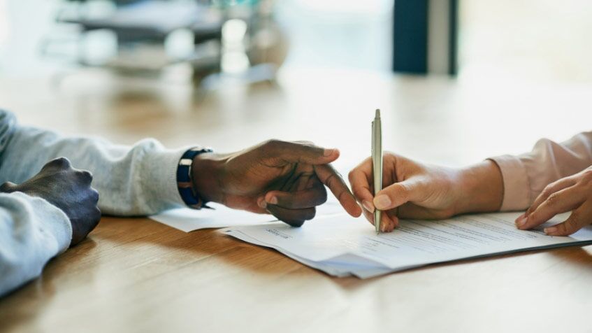 Woman Hand Filling Form On Table And Another Guy Guiding Her